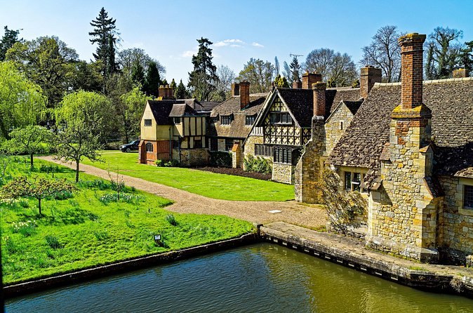 Hever Castle across the water with the Tudor Village roofline behind it