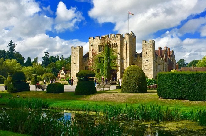The clipped topiary and the moat in front of Hever Castle on a bright afternoon