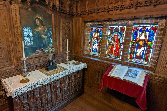 Stained glass above a carved chest and an open book in one of Hever Castle's panelled rooms